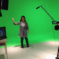 Student gestures in front of green screen, other students work Audio-visual equipment