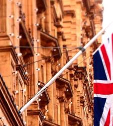 Image of a beige building with lots of detail and the British flag flying in front of it
